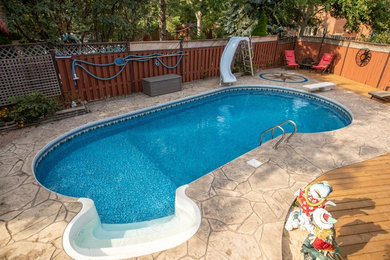 Inspiration for a backyard custom-shaped pool in Toronto with stamped concrete.