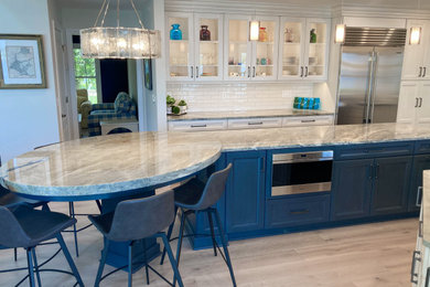 Eat-in kitchen - large traditional u-shaped limestone floor and brown floor eat-in kitchen idea in Cleveland with an undermount sink, recessed-panel cabinets, blue cabinets, quartzite countertops, white backsplash, porcelain backsplash, stainless steel appliances, an island and gray countertops