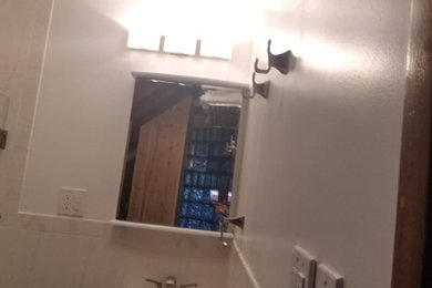 Diseño de cuarto de baño principal y único tradicional de tamaño medio con puertas de armario blancas, ducha esquinera, sanitario de una pieza, baldosas y/o azulejos blancos, baldosas y/o azulejos en mosaico, paredes blancas, suelo de baldosas de porcelana y suelo negro