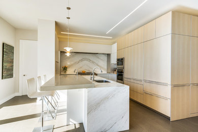 Large modern l-shaped eat-in kitchen in Dallas with an undermount sink, flat-panel cabinets, light wood cabinets, marble benchtops, white splashback, stone slab splashback, stainless steel appliances, ceramic floors and a peninsula.