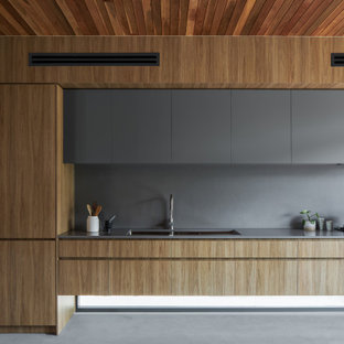 Inspiration for a modern galley kitchen in Brisbane with an undermount sink, flat-panel cabinets, light wood cabinets, grey splashback, panelled appliances, with island, grey floor, grey benchtop and wood.