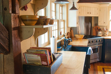 Inspiration for a mid-sized country l-shaped open concept kitchen remodel in Newark with no island, flat-panel cabinets, black cabinets, wood countertops and beige backsplash