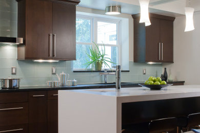 Enclosed kitchen - mid-sized contemporary galley medium tone wood floor, brown floor and coffered ceiling enclosed kitchen idea in St Louis with an undermount sink, flat-panel cabinets, dark wood cabinets, quartz countertops, gray backsplash, glass tile backsplash, stainless steel appliances, an island and white countertops