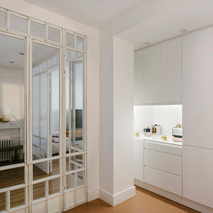 Modelo de cocina lineal, contemporánea, cerrada, sin isla, con fregadero de un seno, puertas de armario blancas, encimera de cuarzo compacto, salpicadero blanco, electrodomésticos negros, suelo de baldosas de porcelana, suelo rojo y encimeras blancas