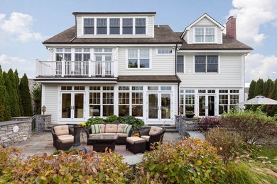 Example of a classic gray three-story wood exterior home design in New York with a hip roof