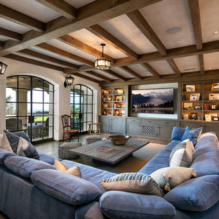 Mediterranes Wohnzimmer ohne Kamin mit beiger Wandfarbe, braunem Holzboden, Multimediawand und braunem Boden in Santa Barbara