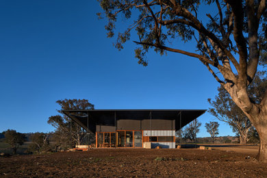 Réalisation d'une grande façade de maison multicolore champêtre de plain-pied avec un toit plat, un toit en métal et un toit gris.