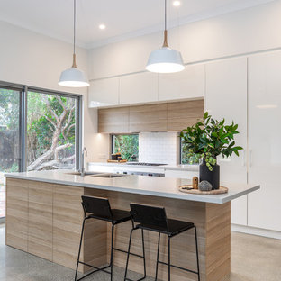 Mid-sized contemporary kitchen pantry ideas - Mid-sized trendy galley concrete floor and gray floor kitchen pantry photo in Adelaide with an undermount sink, flat-panel cabinets, light wood cabinets, quartz countertops, white backsplash, subway tile backsplash, stainless steel appliances, an island and gray countertops