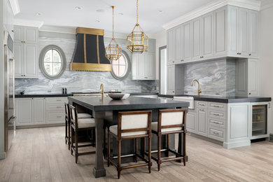 Eat-in kitchen - large transitional l-shaped light wood floor eat-in kitchen idea in Calgary with a farmhouse sink, gray cabinets, gray backsplash, stainless steel appliances, an island and shaker cabinets