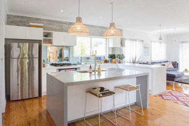 Inspiration for a large scandinavian l-shaped light wood floor eat-in kitchen remodel in Other with flat-panel cabinets, white cabinets, stainless steel appliances, an island, a double-bowl sink, quartz countertops, white backsplash and glass tile backsplash