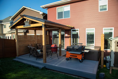 Small minimalist backyard ground level deck photo in Edmonton with a roof extension