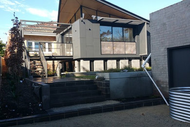 Photo of a mid-sized modern two-storey grey house exterior in Melbourne with mixed siding, a hip roof and a tile roof.