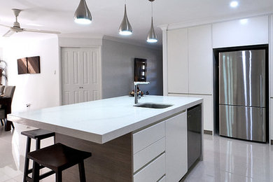 This is an example of a modern kitchen in Brisbane with white cabinets, ceramic floors and with island.