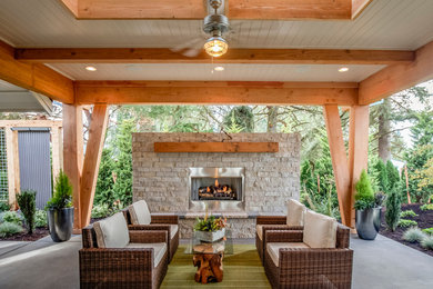 This is an example of a mid-sized country backyard patio in Portland with a fire feature, concrete slab and a roof extension.