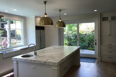 Design ideas for a large transitional u-shaped eat-in kitchen in San Francisco with an undermount sink, recessed-panel cabinets, white cabinets, marble benchtops, grey splashback, stone slab splashback, stainless steel appliances, light hardwood floors, with island, beige floor and grey benchtop.