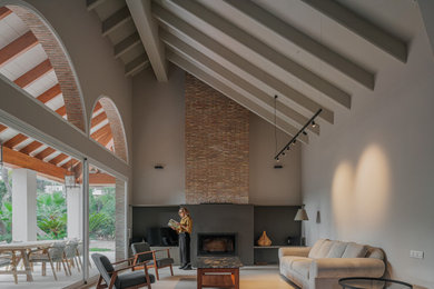 Foto de sala de estar abierta clásica renovada extra grande con paredes grises, suelo de baldosas de porcelana, todas las chimeneas, marco de chimenea de ladrillo, suelo gris y vigas vistas