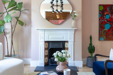 Large victorian open plan living room in London with light hardwood flooring, a standard fireplace and a metal fireplace surround.