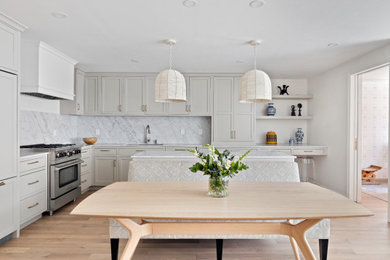 Example of a transitional l-shaped light wood floor and beige floor kitchen design in Dallas with an undermount sink, shaker cabinets, gray cabinets, gray backsplash, an island and white countertops