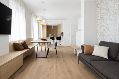 Foto di un soggiorno minimalista di medie dimensioni e aperto con pareti bianche, parquet chiaro, TV a parete, pavimento marrone e carta da parati