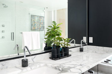 Large trendy master marble floor, white floor and double-sink bathroom photo in Vancouver with flat-panel cabinets, black cabinets, black walls, an undermount sink, marble countertops, a hinged shower door, white countertops and a built-in vanity