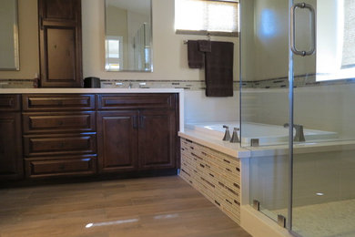 Mid-sized transitional master bathroom in Orange County with raised-panel cabinets, dark wood cabinets, a drop-in tub, an alcove shower, beige tile, glass tile, beige walls, ceramic floors, an undermount sink and granite benchtops.