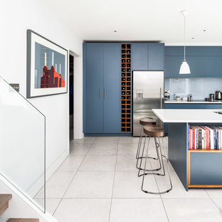 This is an example of a contemporary kitchen/diner in London with flat-panel cabinets, composite countertops, grey splashback, glass sheet splashback, stainless steel appliances, porcelain flooring and an island.