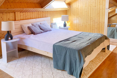 Imagen de dormitorio tipo loft y blanco y madera rústico de tamaño medio con paredes marrones, suelo laminado, suelo marrón, techo inclinado, madera y con escritorio