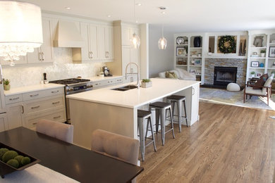 Example of a mid-sized minimalist single-wall medium tone wood floor eat-in kitchen design in Calgary with an undermount sink, shaker cabinets, gray cabinets, quartz countertops, white backsplash, stone tile backsplash, stainless steel appliances and an island