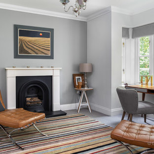 This is an example of a medium sized modern home office and library in Other with a reading nook, grey walls, carpet, a standard fireplace, a stone fireplace surround, a freestanding desk and grey floors.