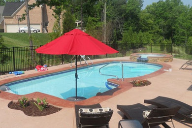 Elegant backyard concrete paver and custom-shaped hot tub photo in Raleigh