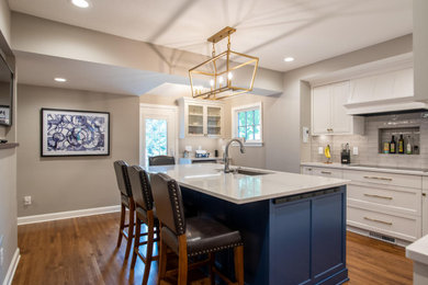 Enclosed kitchen - traditional light wood floor enclosed kitchen idea in Minneapolis with an undermount sink, recessed-panel cabinets, blue cabinets, quartz countertops, gray backsplash, glass tile backsplash, stainless steel appliances, an island and white countertops