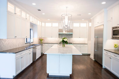 Example of a large transitional u-shaped dark wood floor and brown floor eat-in kitchen design in Dallas with an undermount sink, white cabinets, marble countertops, gray backsplash, marble backsplash, stainless steel appliances and an island