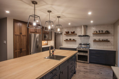 Example of a large transitional medium tone wood floor and brown floor eat-in kitchen design in Ottawa with an undermount sink, shaker cabinets, medium tone wood cabinets, solid surface countertops, white backsplash, porcelain backsplash, stainless steel appliances and an island