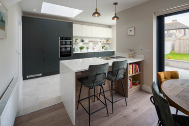 Medium sized contemporary galley kitchen/diner in Dublin with a single-bowl sink, flat-panel cabinets, white cabinets, composite countertops, white splashback and white worktops.