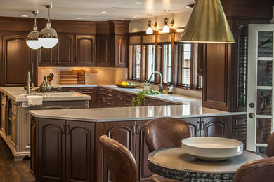 Large transitional l-shaped medium tone wood floor and brown floor eat-in kitchen photo in Denver with a drop-in sink, raised-panel cabinets, medium tone wood cabinets, marble countertops, paneled appliances and an island