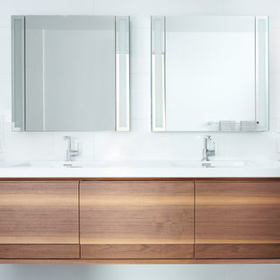 Inredning av ett modernt mellanstort vit vitt en-suite badrum, med släta luckor, skåp i mellenmörkt trä, en toalettstol med separat cisternkåpa, vit kakel, glaskakel, vita väggar, klinkergolv i porslin, ett integrerad handfat, grått golv och med dusch som är öppen