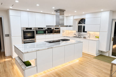 Large minimalist light wood floor and brown floor eat-in kitchen photo in Kansas City with an undermount sink, flat-panel cabinets, white cabinets, quartz countertops, white backsplash, quartz backsplash, stainless steel appliances, an island and white countertops