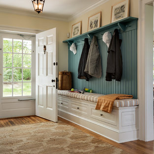 ニューヨークの大きい片開きドアトラディショナルスタイルのおしゃれなマッドルーム (黄色い壁、白いドア) の写真