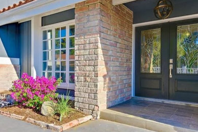 This is an example of a mid-sized traditional concrete paver front porch design in Orange County with a roof extension.