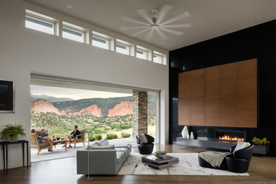 Design ideas for an expansive contemporary open concept living room in Denver with grey walls, dark hardwood floors, a ribbon fireplace, a stone fireplace surround and a concealed tv.