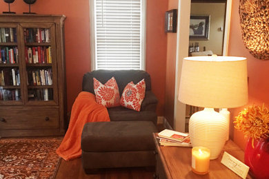 Diseño de despacho contemporáneo pequeño con parades naranjas, suelo de madera oscura, escritorio independiente y suelo marrón