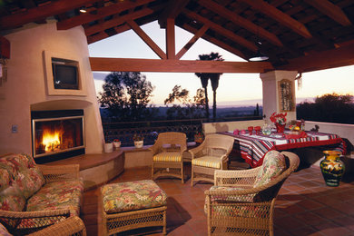 Mediterranean family room in Santa Barbara with terra-cotta floors, a standard fireplace and a built-in media wall.