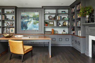 Transitional home office in Toronto with grey walls, dark hardwood floors, a standard fireplace, a freestanding desk and brown floor.