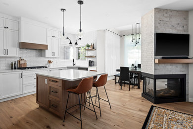 Inspiration for a large farmhouse u-shaped medium tone wood floor and brown floor eat-in kitchen remodel in Calgary with an undermount sink, shaker cabinets, white cabinets, ceramic backsplash, black appliances, an island, quartz countertops, white backsplash and white countertops