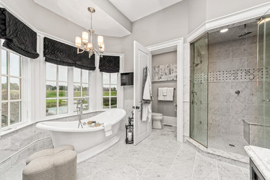 Design ideas for a large transitional master bathroom in Columbus with recessed-panel cabinets, dark wood cabinets, a freestanding tub, gray tile, marble, grey walls, marble floors, an undermount sink, grey floor and white benchtops.