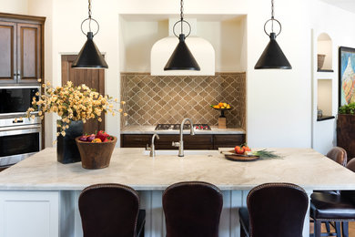 This is an example of a mid-sized mediterranean l-shaped open plan kitchen in Phoenix with a farmhouse sink, raised-panel cabinets, dark wood cabinets, quartzite benchtops, terra-cotta splashback, stainless steel appliances, medium hardwood floors, with island, brown floor, beige benchtop and beige splashback.