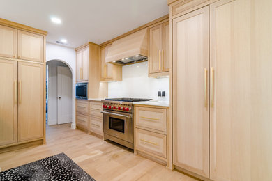 Bild på ett mellanstort vintage vit vitt kök, med en rustik diskho, skåp i shakerstil, skåp i ljust trä, bänkskiva i kvarts, vitt stänkskydd, integrerade vitvaror, ljust trägolv och en köksö