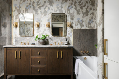 Inspiration for a mid-sized transitional gray tile and stone tile limestone floor, gray floor, double-sink and wallpaper alcove bathtub remodel in San Francisco with medium tone wood cabinets, multicolored walls, an undermount sink, marble countertops, a hinged shower door, gray countertops, a niche and a built-in vanity