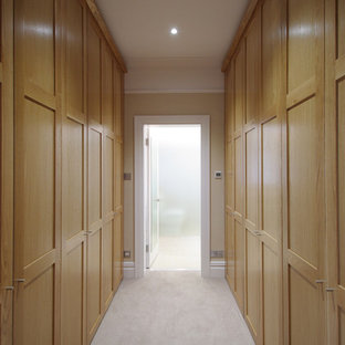 Medium sized modern gender neutral dressing room with shaker cabinets, medium wood cabinets and carpet.