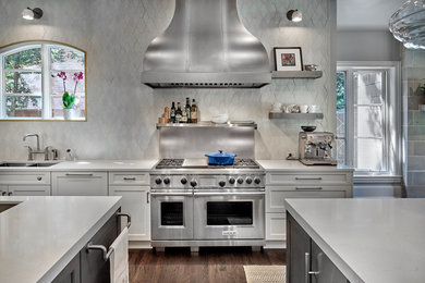 Inspiration for a large transitional u-shaped open plan kitchen in Dallas with a double-bowl sink, shaker cabinets, white cabinets, quartz benchtops, white splashback, cement tile splashback, stainless steel appliances, dark hardwood floors, multiple islands, brown floor and white benchtop.